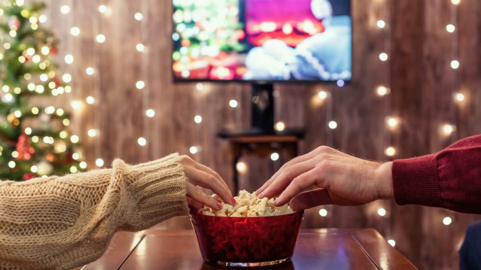 Couple watching a film while sharing popcorn at Christmas